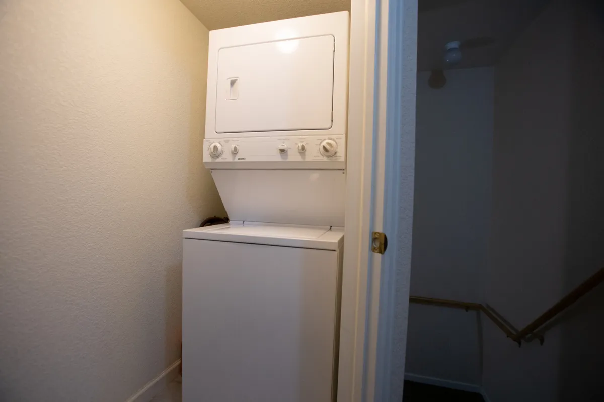 The photo focuses on a clean, practical laundry area with a washer and dryer set alongside a staircase. The space is bright and functional, suggesting ease of handling chores and readiness for the next outing.