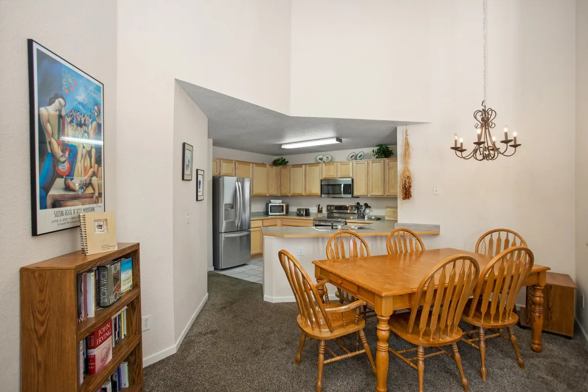 A welcoming dining and kitchen area with a central table, open shelving, and windows bringing in natural light. The space feels sociable and relaxed, ideal for gathering after outdoor activities.