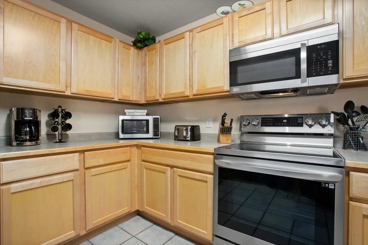 A cozy kitchen scene with kitchen appliances, generous countertop space, and warm wood cabinetry. The layout is perfect for preparing meals, socializing, or even working from the kitchen. The welcoming mood underscores the inviting, home-away-from-home vibe ideal for longer stays.