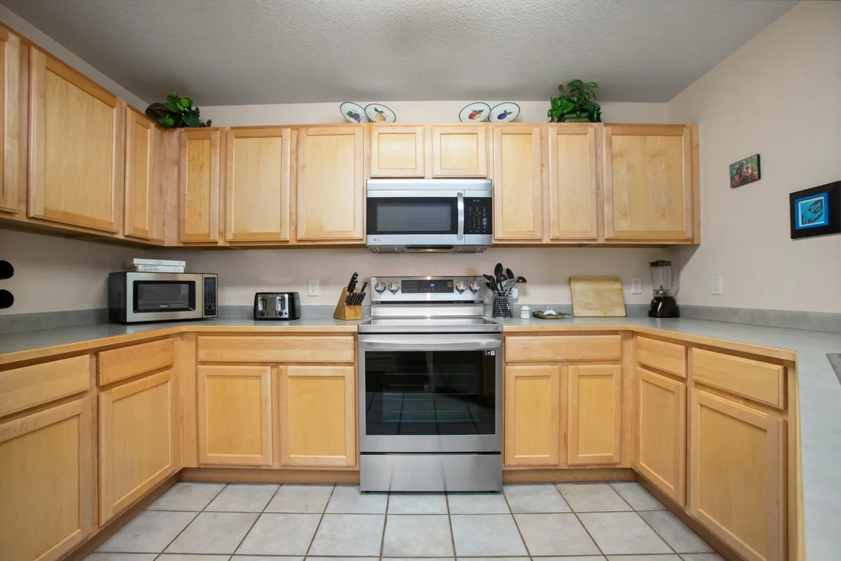 A spacious kitchen with stainless steel appliances, generous counter space, and wooden cabinets, reinforcing the welcoming atmosphere for shared cooking and entertaining. The scene is well-lit and designed for social interaction.