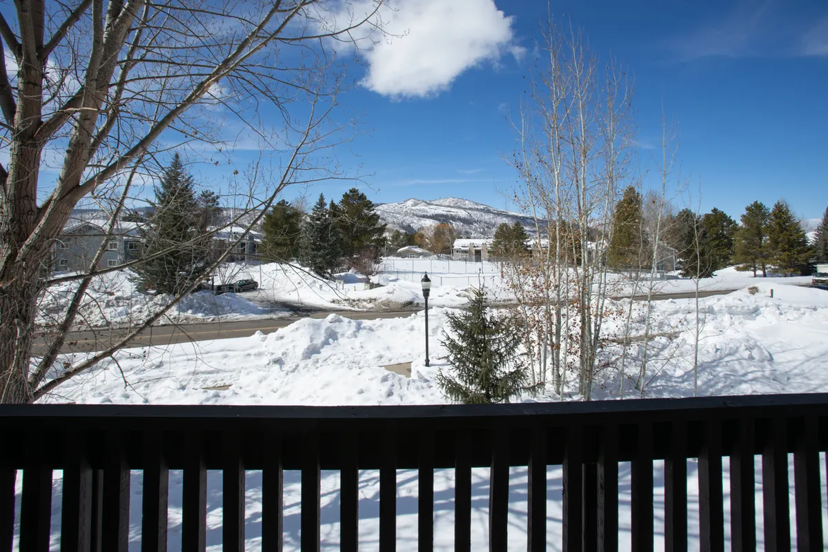 A peaceful winter landscape featuring snow-covered ground, distant mountains, bare trees, and a glowing lamp post. The scene is serene, inviting thoughts of snowball fights, snowman-building, and relaxing after winter adventures.
